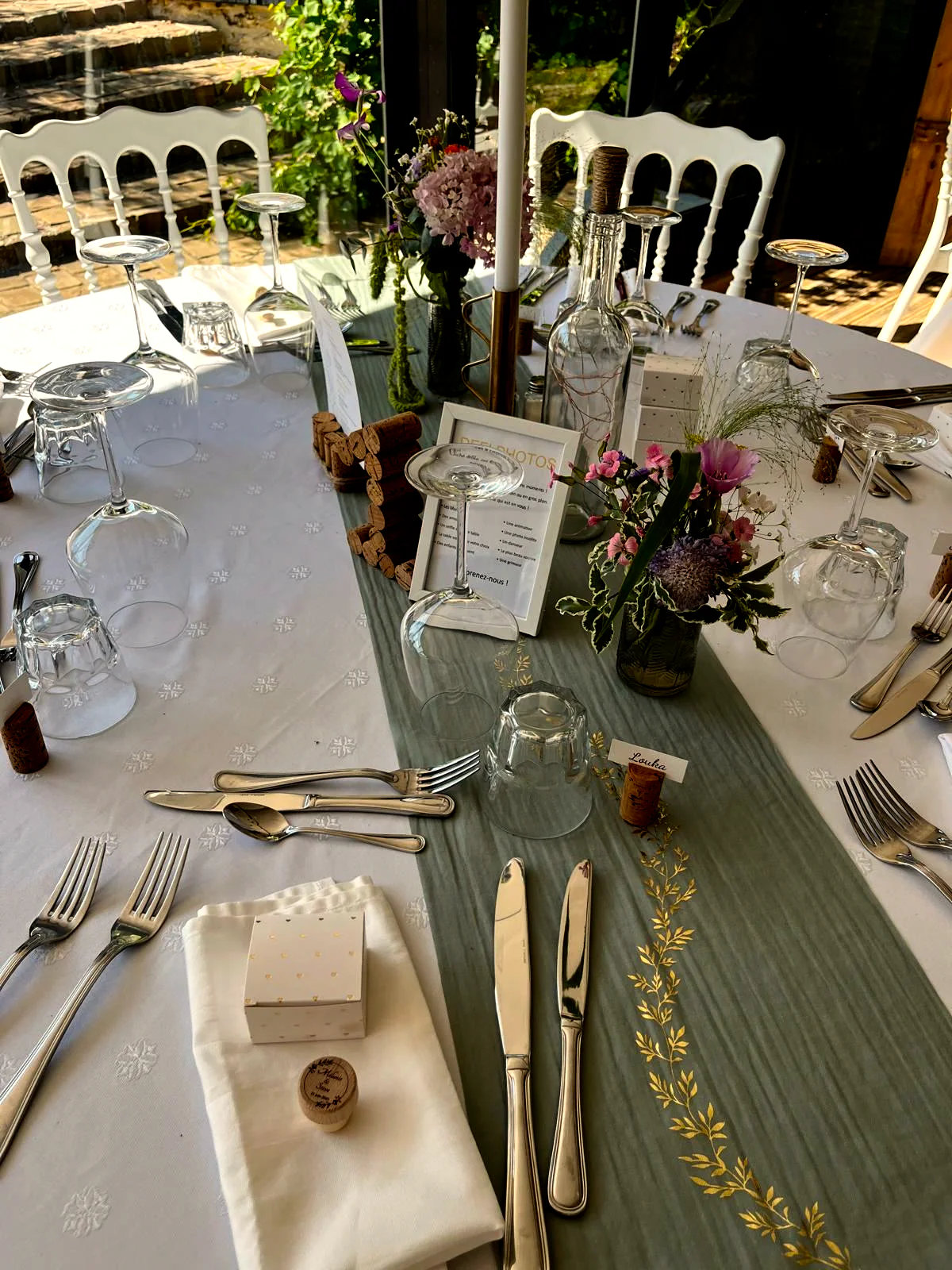 Une table dressée : couverts, verres, menu et petit bouquet