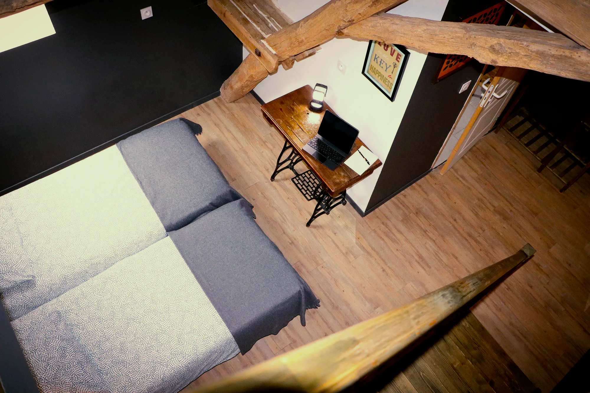 Une chambre vue d'en haut : banquette, bureau et poutres apparentes